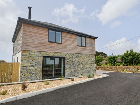 A two-story house with stone and wood exterior walls and a black-tiled roof at 3 Praa Cove in Praa Sands