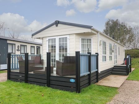 A static caravan with a glass enclosed patio and outdoor seating at The Bobbin Number 11 in South Lakeland Leisure Village near Carnforth