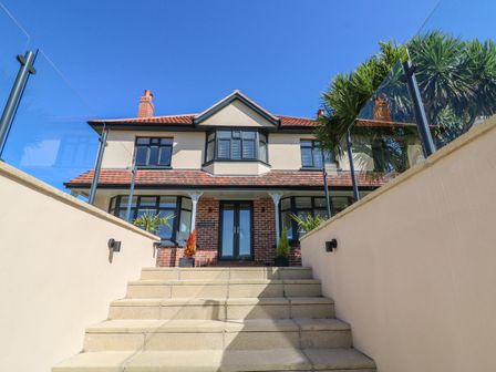 Front view of a two-story house with steps leading to the entrance at Greenbank in Woolacombe