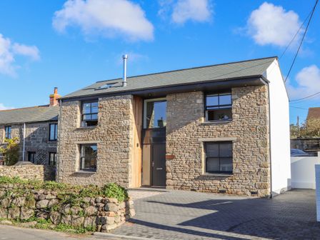 A stone house with black framed windows and a paved driveway at Bal An Mor in Pendeen
