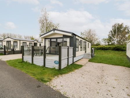 A mobile home with a fenced patio and outdoor furniture on a grassy and gravel area at Number 10 in Warton