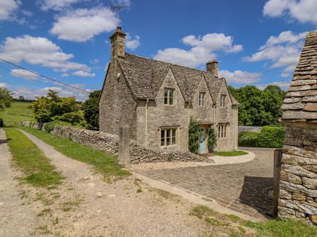 A stone cottage with a tiled roof by a gravel road and stone walls at No 1 Eastington in Eastington near Northleach