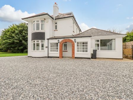 A white two story house with a red brick arch entryway and gravel driveway at Pen-Y-Thon House in Summercourt
