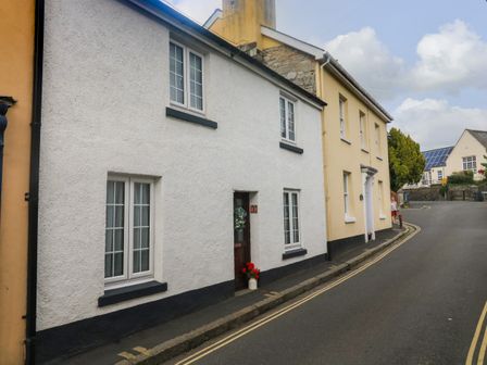 A street view with white and yellow houses along a curved road with double yellow lines at Hope Cottage in Buckfastleigh