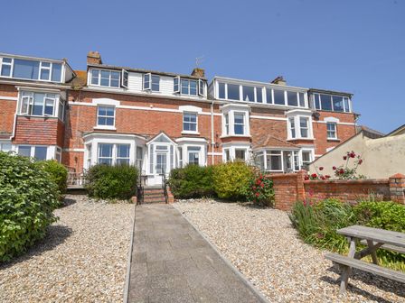 A brick terraced house with white window frames and a pathway leading to the front door at 3 Cobb View Lyme Regis