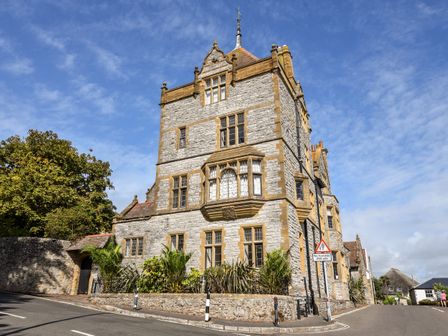 A stone building with multiple windows and a sign on the street at 3 Coram Tower in Lyme Regis
