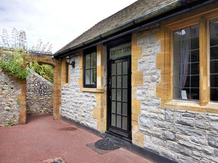 Stone building exterior with arched entrance and black door at Coram Lodge in Lyme Regis