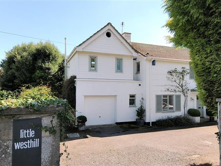A white house with a garage and plants near the entrance at Little West Hill Studio in Lyme Regis