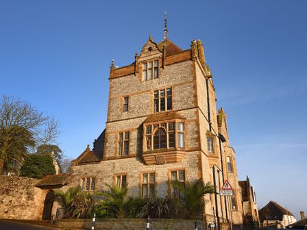 A large stone building with multiple windows and a tiled roof next to a street with a no footway sign at 1 Coram Tower in Lyme Regis