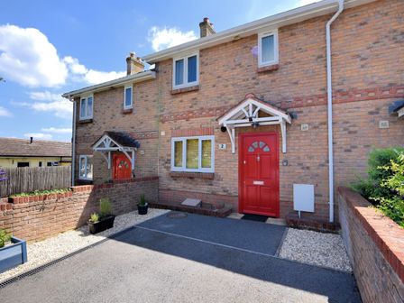 The exterior of a brick house with a red front door and a driveway at 2 Coppers Knapp in Lyme Regis
