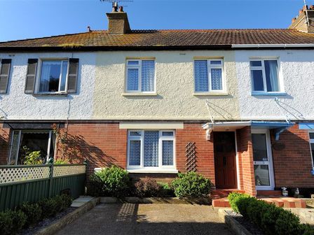 A terraced house with brick and stucco exterior a brown door and front garden at 23 Lym Close Lyme Regis