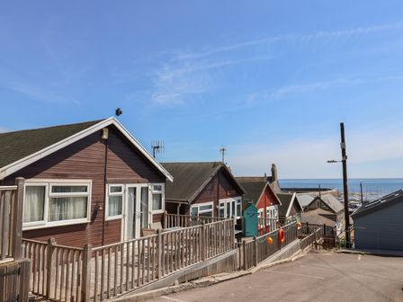 A row of wooden cabins with railings and a view of the sea at Granny's Teeth in Lyme Regis