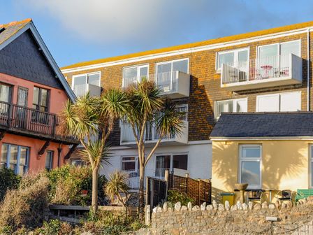 Exterior view of multi-story buildings with balconies and palm trees in front at 1 Bay View Court in Lyme Regis