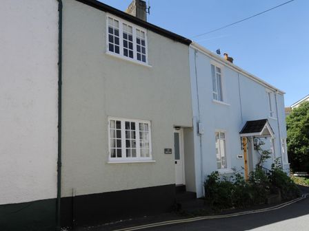 A street view of two adjoining houses one with a cream exterior and the other with a light blue exterior at 17 Mill Green Lyme Regis