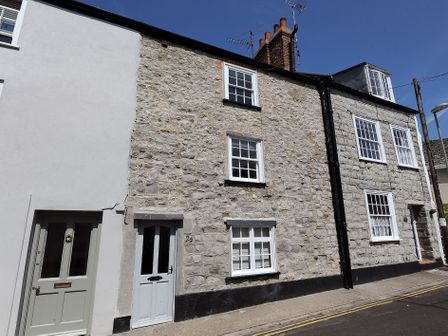 A street view of stone and white painted houses with multiple windows and doors at 24 Mill Green in Lyme Regis