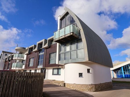 A modern apartment building with balconies and large windows at 2 Driftwood in West Bay