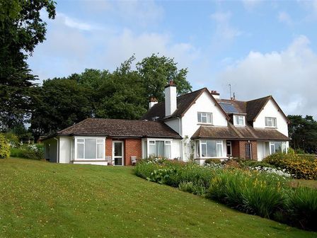 A large house with a garden and trees in the background at West Ridge Bungalow in Seaton Devon