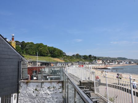 A beach with people on the sand and a row of houses along the shore at Gull Cottage in Lyme Regis