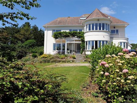 A large house with a sloped roof and multiple windows surrounded by a garden with flowers and shrubs at Westdale Edge in Seaton Devon