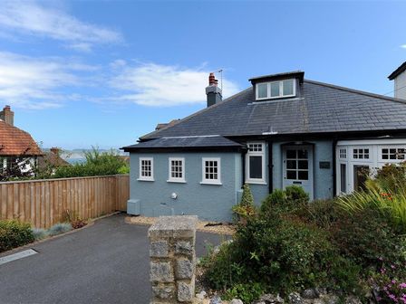 The exterior of a blue house with a black roof driveway wooden fence and shrubs at Highpoint Lodge in Lyme Regis