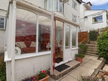 A garden patio with potted plants and steps leading up to a wooden gate at Bay View in Lyme Regis