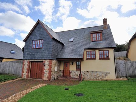 A house with a garage and a front door with windows on a lawn at 28 Barnes Meadow in Uplyme