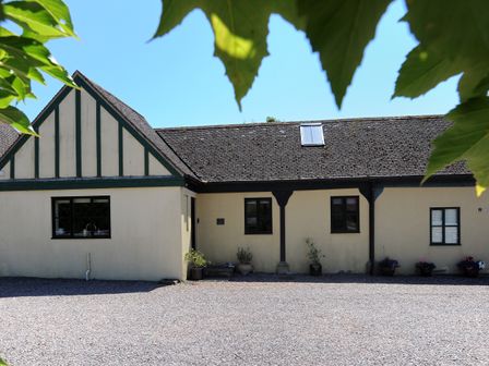 A building with a tiled roof and multiple windows with potted plants outside at 3 Home Farm South in Rousdon