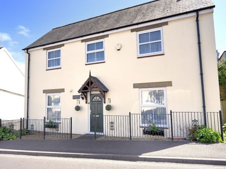 A two story house with four windows a green door and metal railings at Vine Cottage in Charmouth