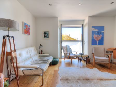 A living room with wooden floor a white sofa two armchairs and a floor lamp at Lyme Time in Lyme Regis