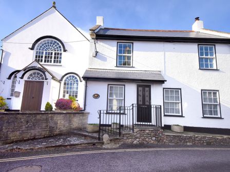 A white building with windows and a small front entrance next to a Methodist Church at Sunnyside in Colyton