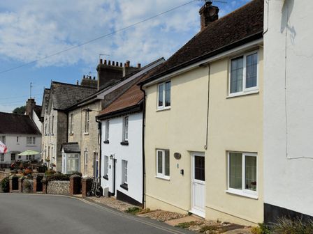 A row of houses along a street with stone and painted walls and various windows
