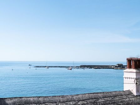 A view of the ocean with a small harbor and boats near a rooftop at 2 Beach Way House in Lyme Regis