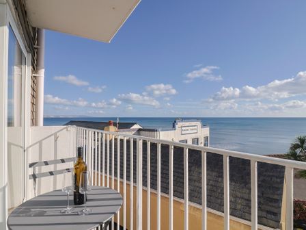 A balcony with a bottle and glasses overlooking the sea at 6 Bay View Court in Lyme Regis