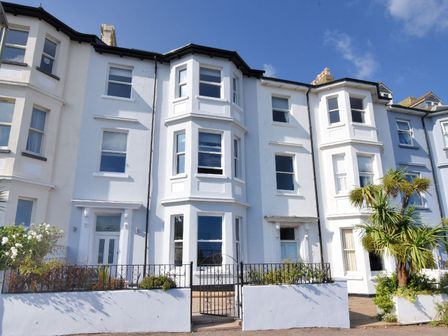 A row of white terraced houses with bay windows and small front gardens at 7 Seafield Road in Seaton