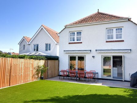 Backyard with dining table and chairs on patio and grass lawn at Lightkeepers Cottage in Lyme Regis
