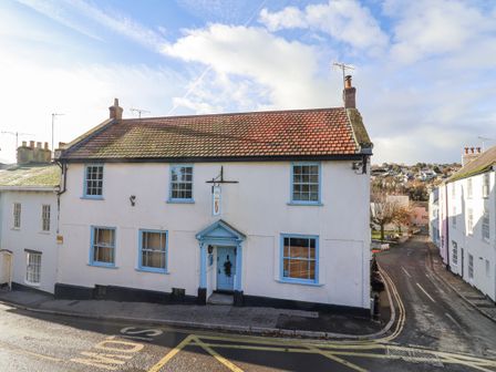 A street corner with a two-story white building with blue window frames and a tiled roof at Old Monmouth in Lyme Regis