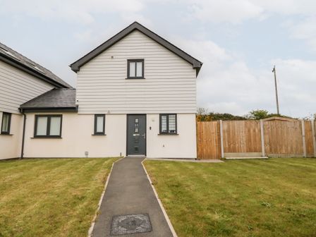 A house with a pathway leading to the front door and a lawn on both sides at 11 Parc Delfryn Brynteg near Benllech