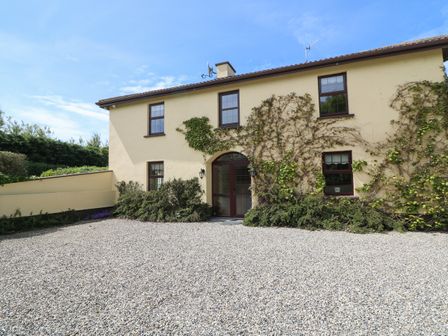 Exterior view of a two-story house with beige walls and climbing plants at Tilladavin House Tomhaggard near Kilmore County Wexford
