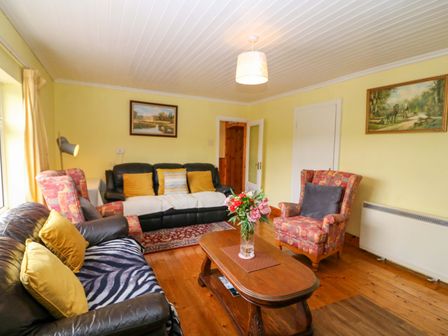 A living room with a sofa, armchair, and coffee table at Forest View in Ballinskelligs, County Kerry