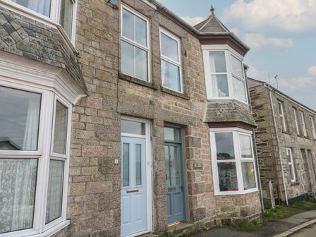 A row of stone townhouses with blue doors and white-framed windows at Rock Lobster in Porthleven
