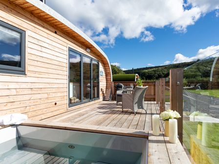 A wooden deck with outdoor seating and a hot tub at High Longlands in Cartmel