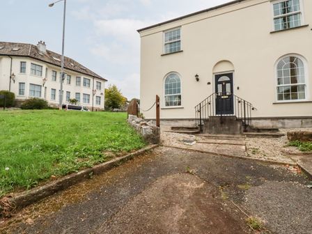 The front entrance of a house with steps leading to a black door and arched windows at 2 Old Talbot Cottages in Lostwithiel