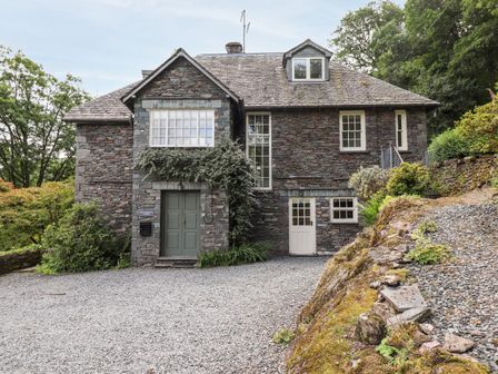 A stone house with green and white doors and gravel driveway at Huntingstile Lodge in Grasmere