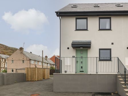 Front view of a modern semi detached house with green door and metal railing at 1 Crud Y Mor in Barmouth