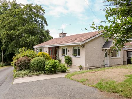 A single story house with surrounded by bushes and trees at Glebe Farm Cottage in Rathfriland County Down