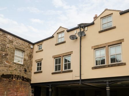 The exterior of a beige building with multiple windows and two satellite dishes mounted on the wall at Lavenna in Alnwick