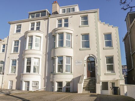 A multi-story residential building with multiple windows and an entrance with stairs at Apartment 2 in Llandudno