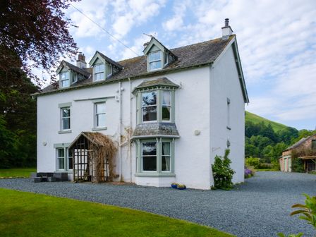 A large white two-story house with green window frames and a gravel driveway surrounded by grass and trees at Swinside Lodge in Newlands Valley near Keswick