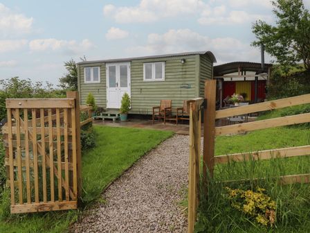 A shepherd's hut with a pathway and gate at The Journeyman Luxury Shepherds Hut in Barnoldswick