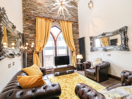 A living room with leather sofas yellow curtains and a fluffy yellow rug at The Upper Room in Ballymena